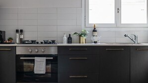 Una cocina moderna con horno empotrado, ventana sobre el fregadero y diversos utensilios de cocina sobre la encimera.