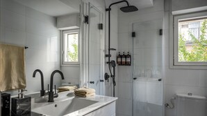 Un baño moderno con un lavamanos grande, una ducha y un inodoro.