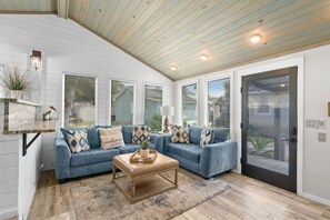 A living room with a sectional sofa, a coffee table, and a glass door leading outside.