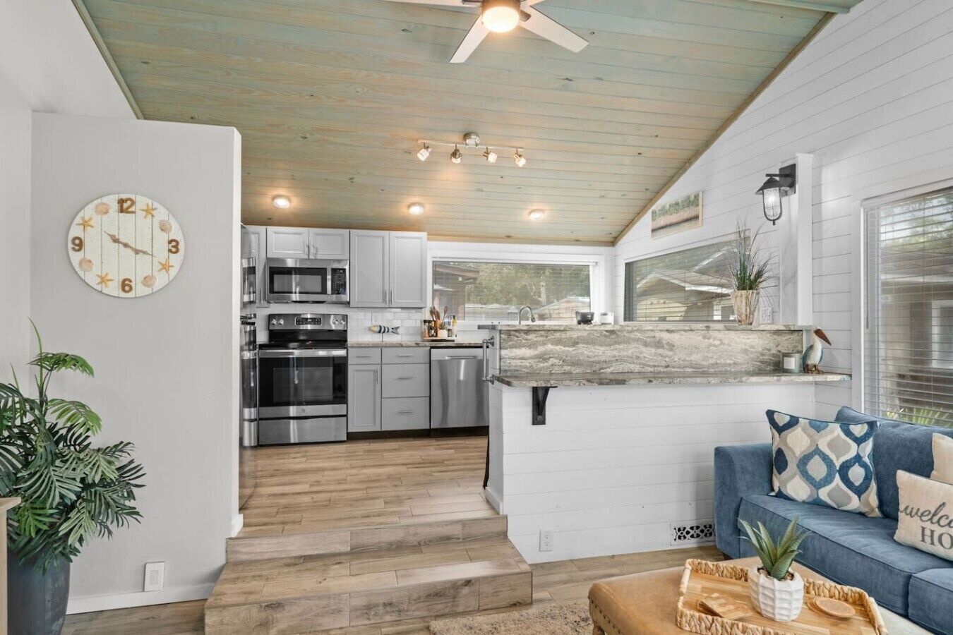 Una cocina moderna con electrodomésticos de acero inoxidable, techo de madera y vista al área de estar.