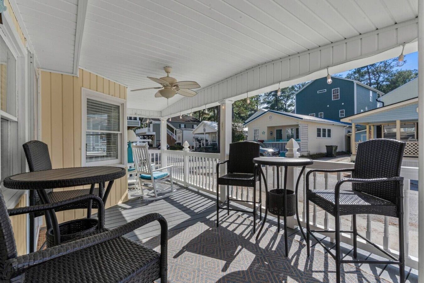 A covered outdoor seating area with wicker furniture and a ceiling fan.