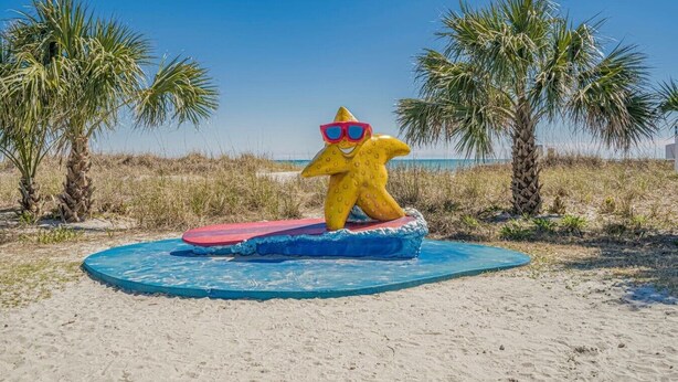 A beach scene with a large yellow starfish sculpture on a blue platform. - Ocean Lakes Cottage, Covered Patio, Grill and Beach! (Myrtle Beach)