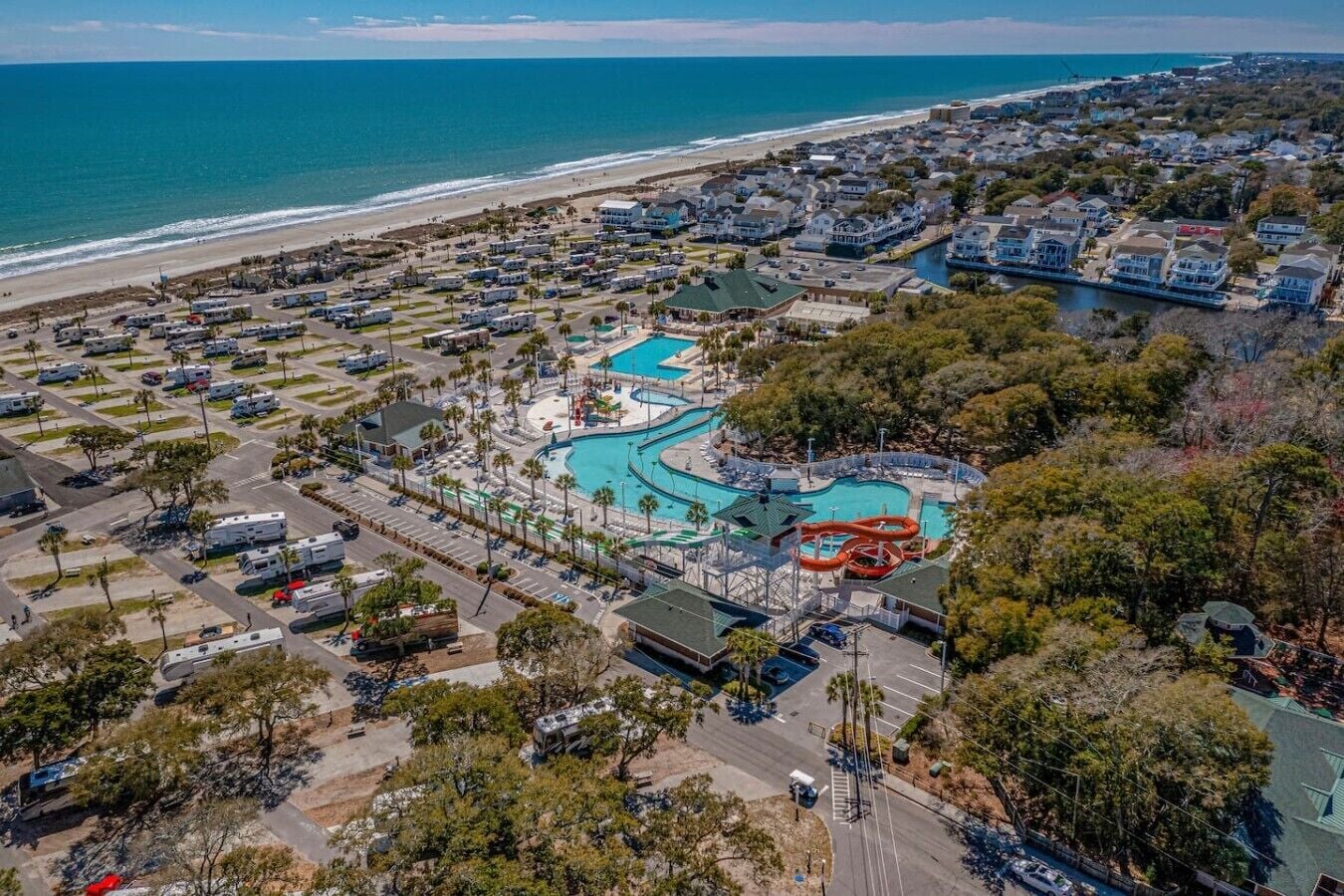Vista aerea di un resort costiero con diverse piscine, un parco acquatico e una spiaggia.