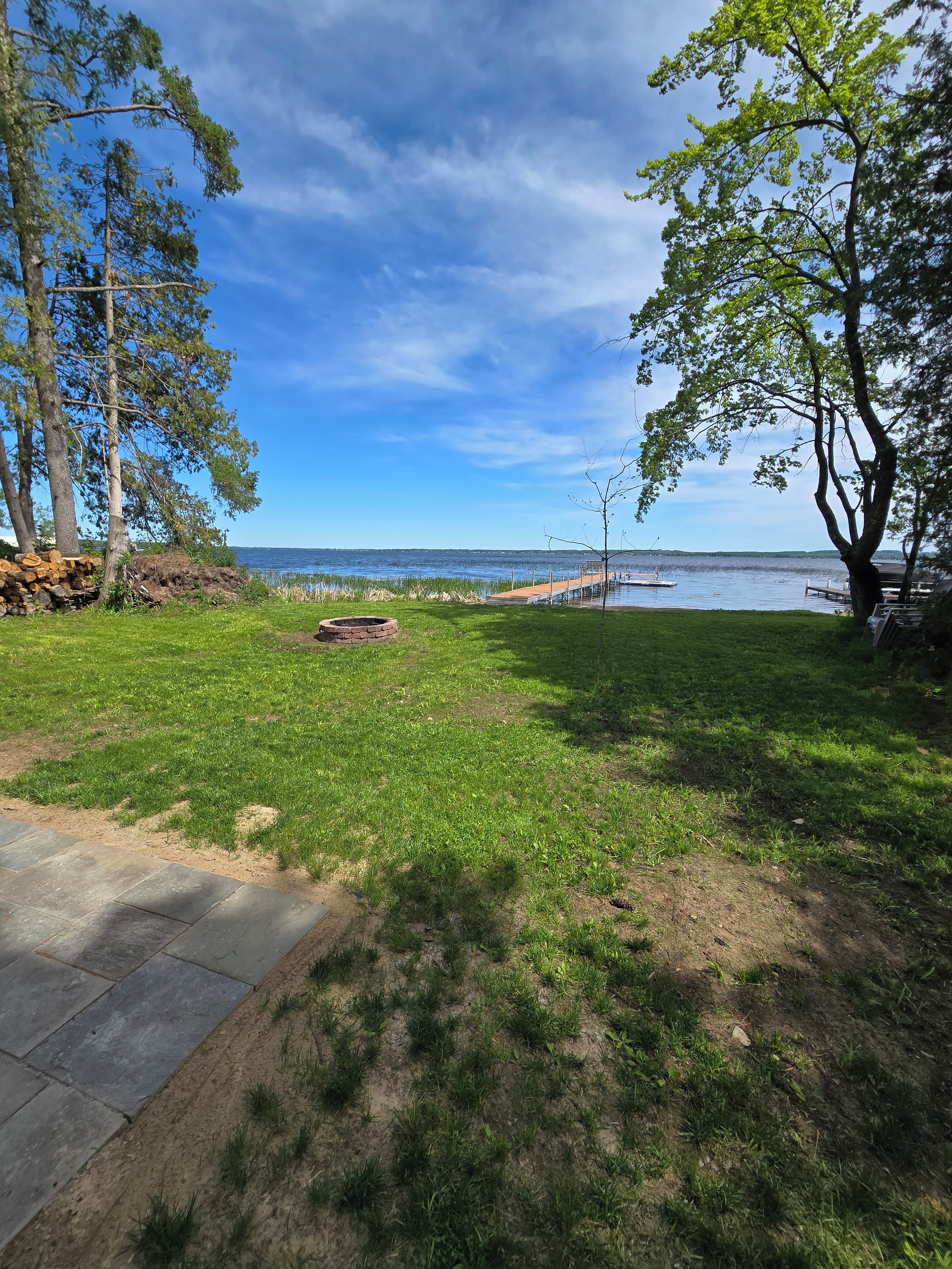 Ein rasengedeckter Garten mit einer Holzterrasse und Blick auf einen See.