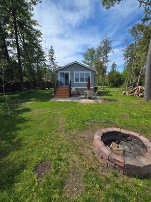 A house with a front porch, a fire pit, and a wooden deck. - The Lily Pad: Newly Renovated, Lakefront Retreat on Shawano Lake, Sleeps 6 (Shawano)