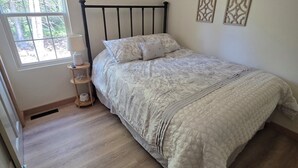 Ein Schlafzimmer mit Bett, Deckenventilator, Fenster und Holzboden.