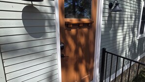 A house with a wooden front door, a mailbox, and two wall-mounted lights. - The Lily Pad: Newly Renovated, Lakefront Retreat on Shawano Lake, Sleeps 6 (Shawano)