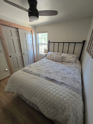 A bedroom with a bed, a ceiling fan, a window, and a door. - The Lily Pad: Newly Renovated, Lakefront Retreat on Shawano Lake, Sleeps 6 (Shawano)