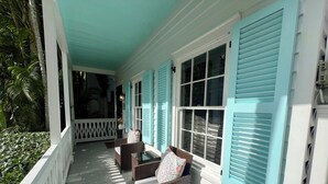 A porch with wicker furniture and a white railing. - Seaport Serenity Cottage - Quiet and Quaint (Key West)