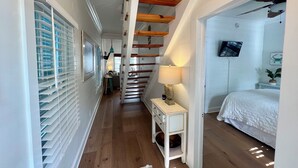 Ein Flur mit Treppe, einem Bett, einem Fernseher und einem kleinen Tisch mit Lampe.