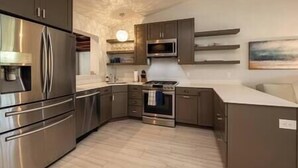 A modern kitchen with stainless steel appliances, wooden cabinets, and a light-colored countertop. - Plumeria Paradise, Your Tropical Retreat Close to the Beach (Key West)