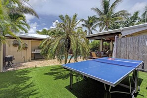 Un patio exterior con mesa de ping pong, una parrilla y una piscina.