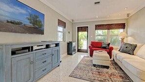 A spacious living room with a large gray entertainment center, a red sofa, and a white couch. - Private & Haven-ly - Pool Home on Boating Canal (Key Haven)