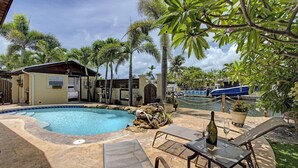 A swimming pool with lounge chairs, a small building, and palm trees. - Private & Haven-ly - Pool Home on Boating Canal (Key Haven)