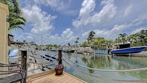 A marina with boats docked, a wooden deck, and a potted plant. - Private & Haven-ly - Pool Home on Boating Canal (Key Haven)