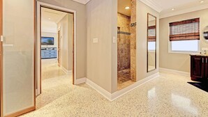 A hallway with a mirrored wall, a shower area with mosaic tiles, and a kitchen visible in the background. - Private & Haven-ly - Pool Home on Boating Canal (Key Haven)