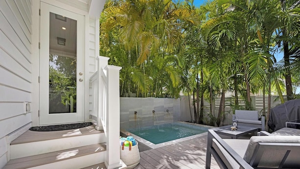 A deck with a hot tub, outdoor furniture, and a view of palm trees. - Southern Skies, Stylish Home in Old Town Key West (Key West)