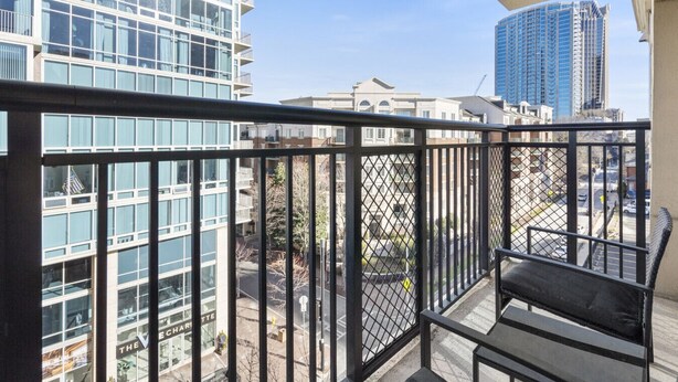 Een balkon met uitzicht op moderne gebouwen en een straat.
