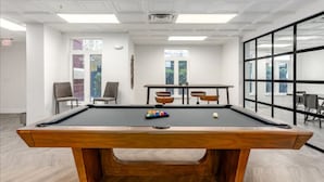 Een pooltafel met stoelen, een raam en een deur met een vluchtbord.