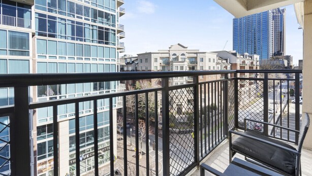 Ein Balkon mit Blick auf umliegende Gebäude, darunter ein modernes Glasgebäude und eine Reihe von Reihenhäusern.