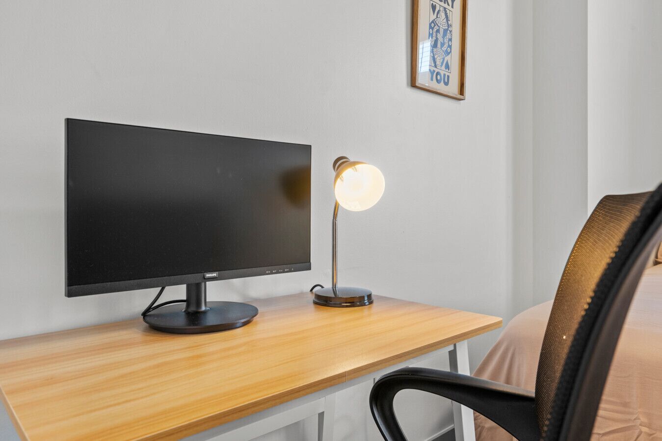 Et moderne arbejdsområde med en fladskærm, en skrivebordslampe og en stol.