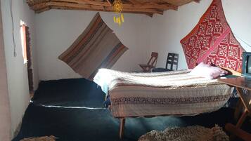 Ein Zimmer mit einem Bett, einem Sessel, einem Fernseher und einem Deckenventilator.