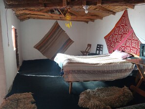 Quarto com cama, poltrona, televisão e ventilador de teto.