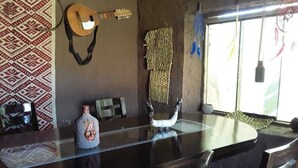 A kitchen with a glass-top table, a guitar, a decorative vase, and a woven wall hanging. - Charming Rural House in Yanaoca (Yanaoca)