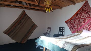 A room with a bed, a chair, and a hanging dreamcatcher.