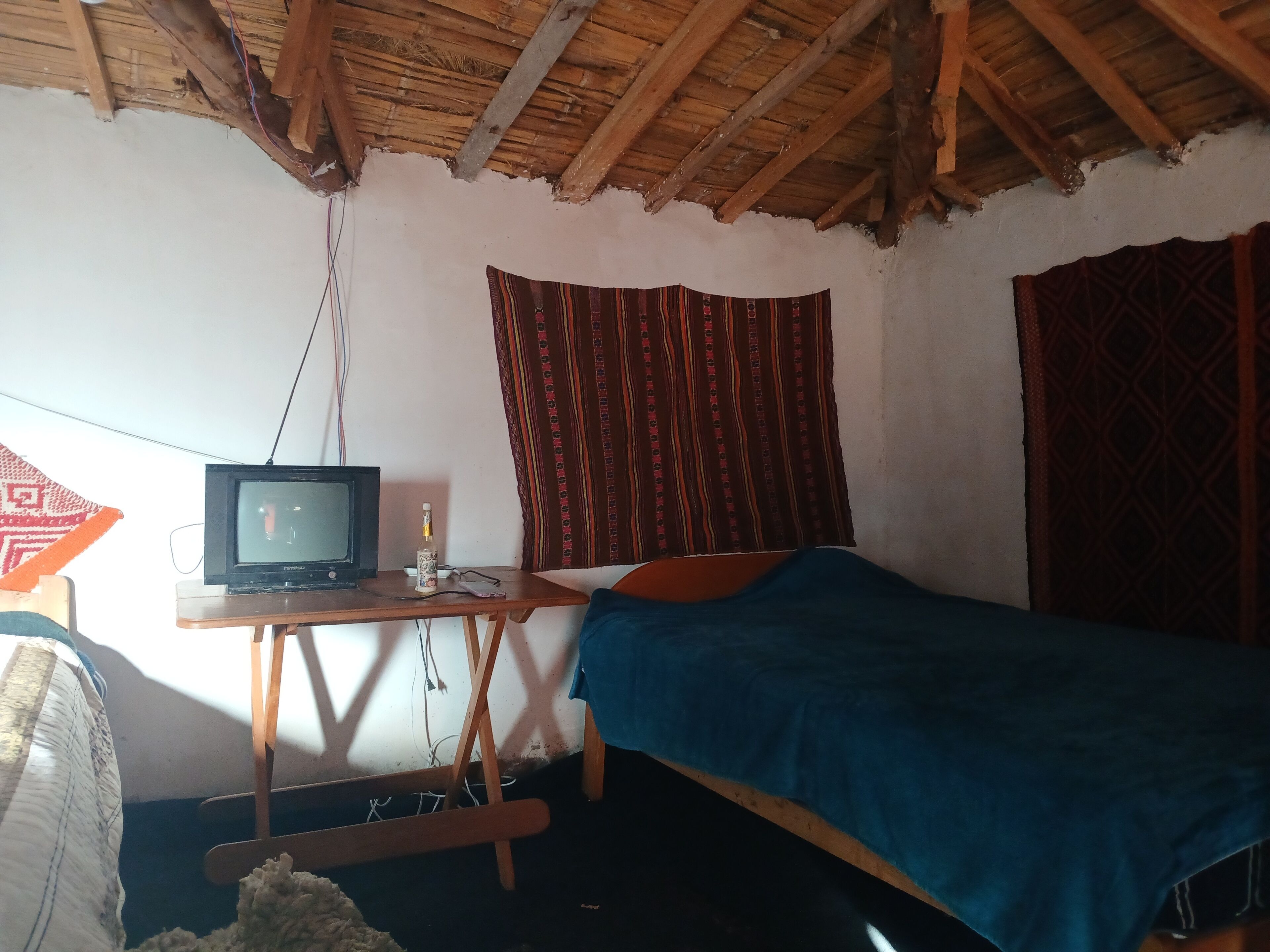 Quarto com uma cama de solteiro, escrivaninha de madeira e cortinas estampadas.