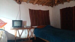A room with a single bed, a wooden desk with a television, and patterned curtains. - Charming Rural House in Yanaoca (Yanaoca)