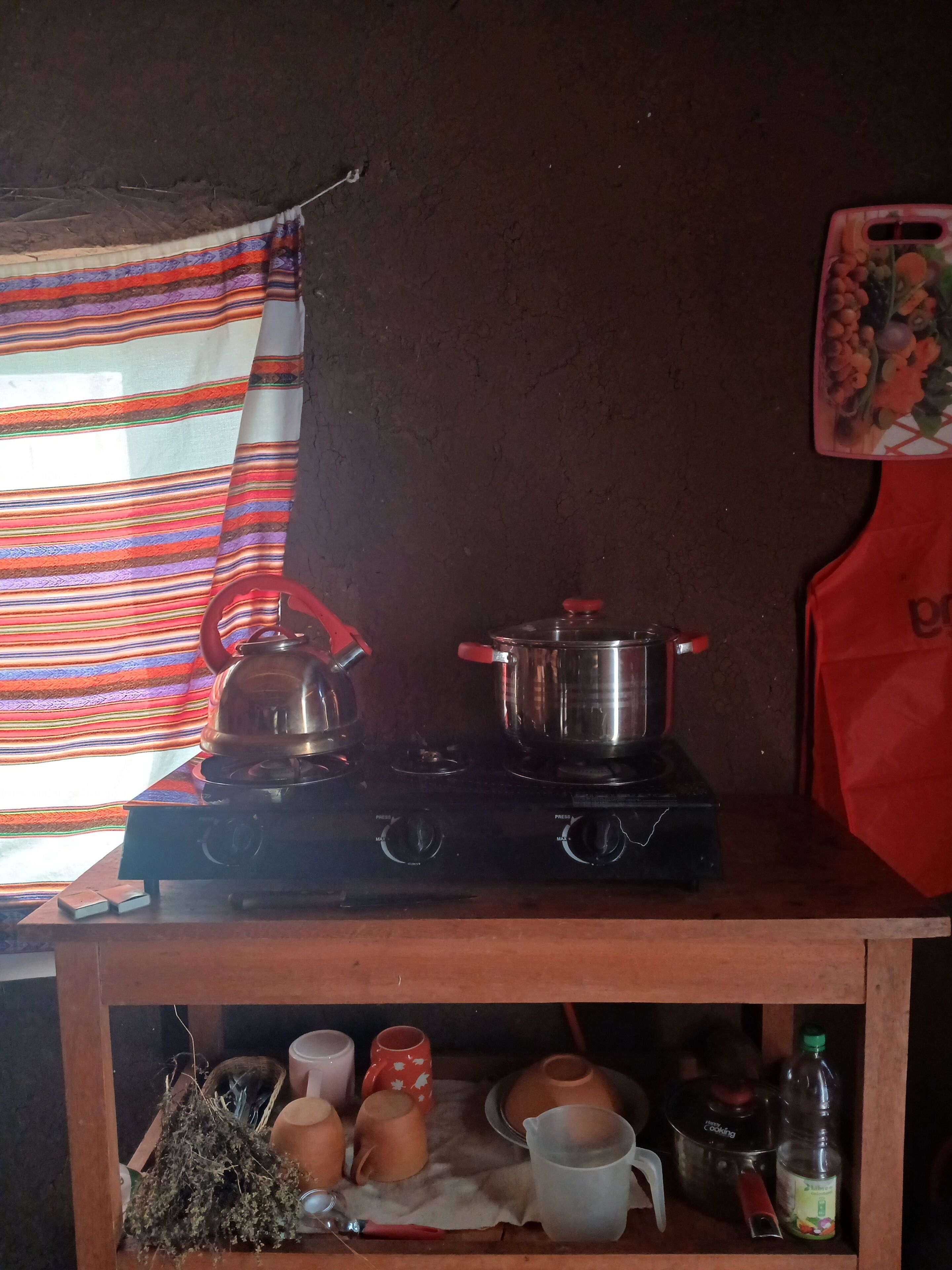 Una cocina con estufa a gas, ollas y diverso menaje de cocina.