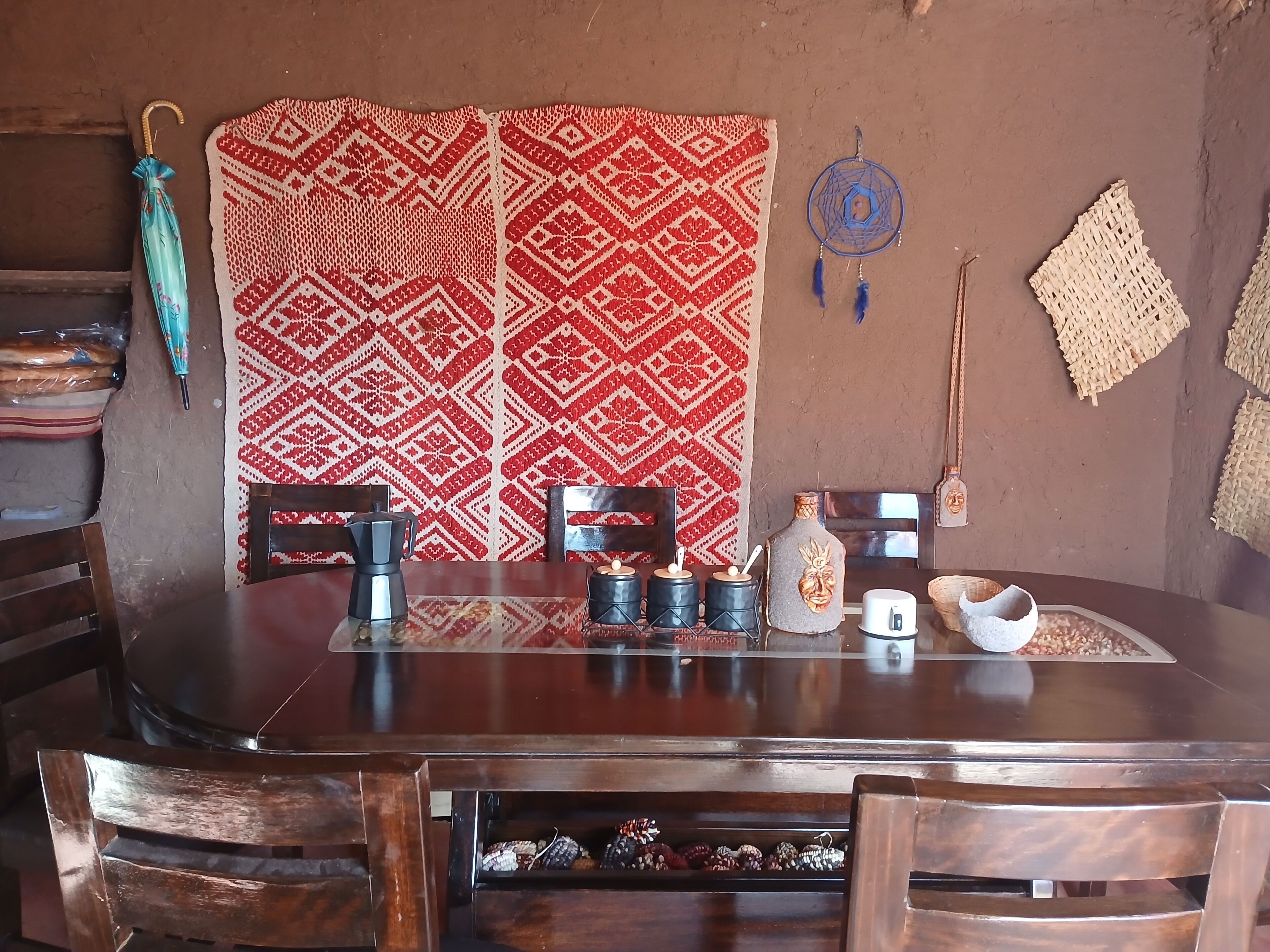 A dining area with a wooden table, chairs, a patterned wall, and various decorative items.