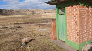 A small brick building with a green door, situated in a rural landscape with hills in the background. - Charming Rural House in Yanaoca (Yanaoca)