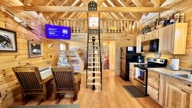 Ein Ferienhausinnenraum mit Holzvertäfelung, einem Essbereich mit Stühlen, einer Küche mit Geräten und einer Treppe.