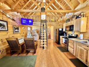A cabin interior with a wooden interior, a dining area with chairs, a kitchen with appliances, and a staircase. - Walleye Point • Where Every Dog Has Its Dale Hollow Day • Free Firewood • Roku TV (Alpine)