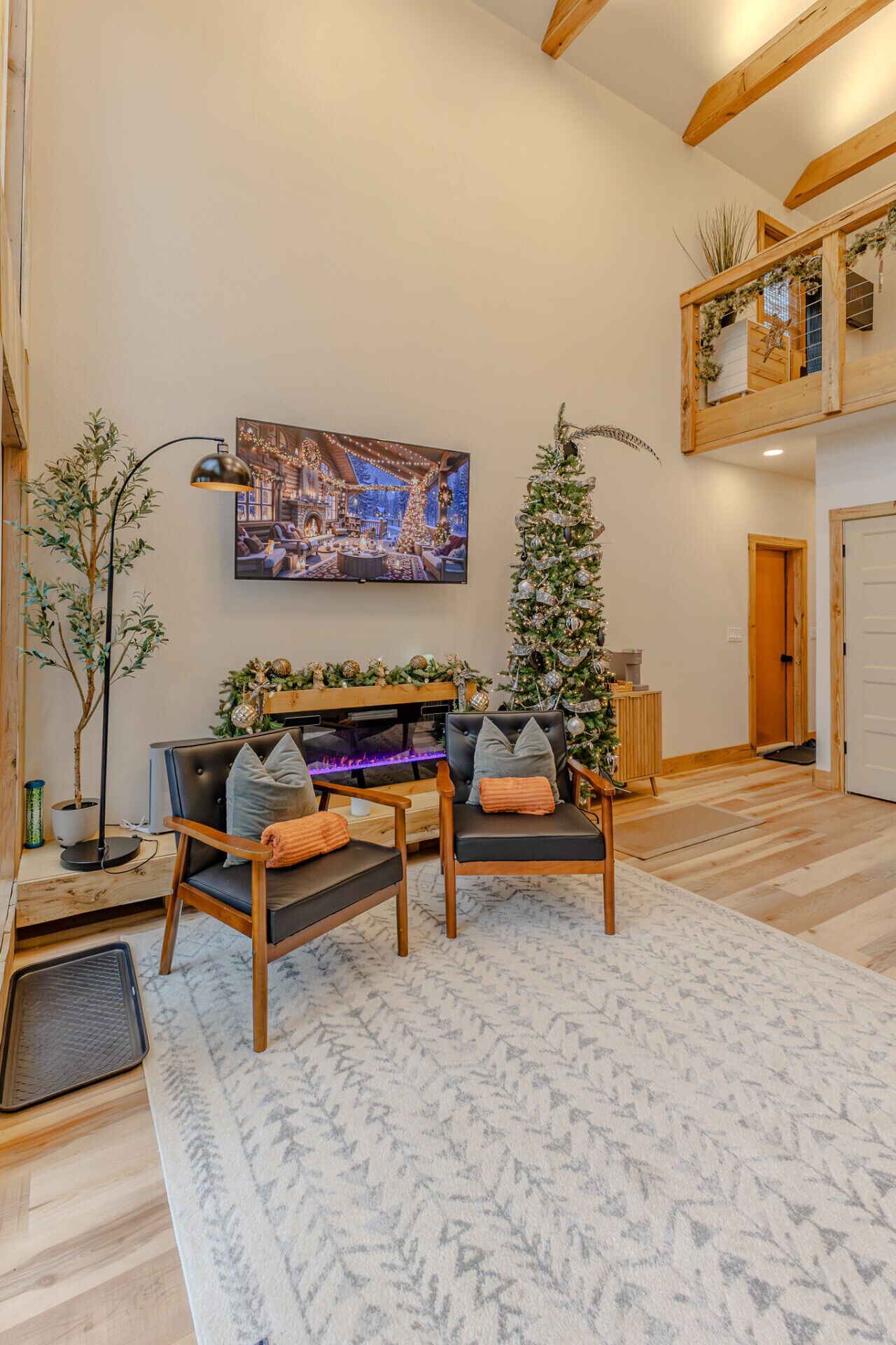 A cozy living room with a fireplace, a large flat-screen TV, a Christmas tree, and a comfortable seating area.