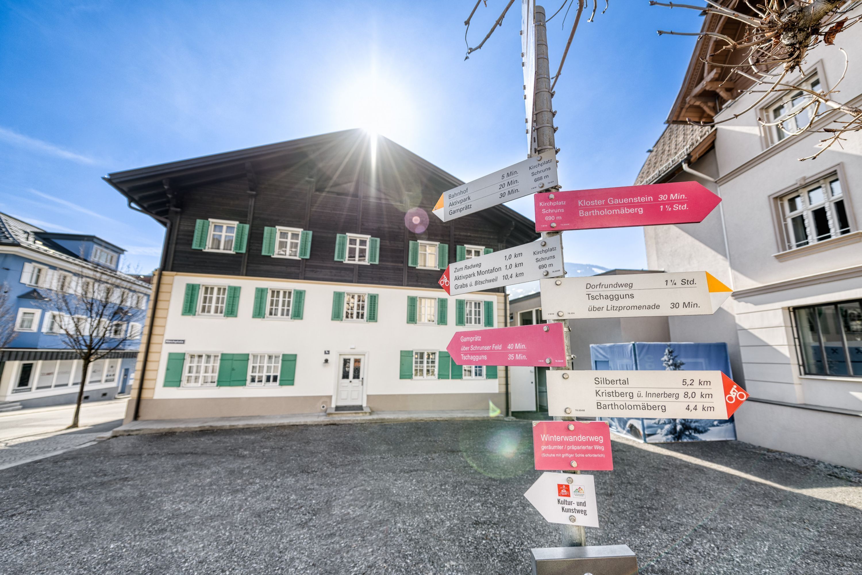 A building with multiple directional signs indicating distances to various locations.