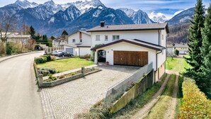 Une propriété résidentielle dotée d’une allée pavée, d’un garage et offrant une vue sur des montagnes enneigées.