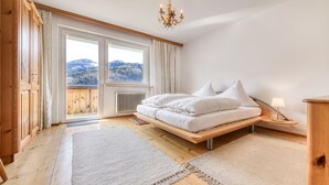 Une chambre à coucher comprenant un lit, une table de chevet, une lampe, une fenêtre donnant sur les montagnes et un lustre.