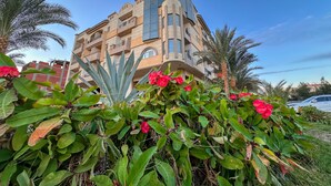 A modern building with balconies and a garden with red flowers. - Fully furnished 02 BR with sea view roof top (Hurghada)