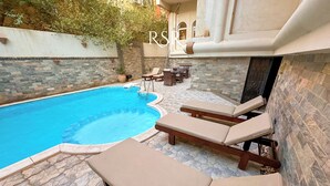 A swimming pool with lounge chairs and a stone-tiled patio. - Fully furnished 02 BR with sea view roof top (Hurghada)