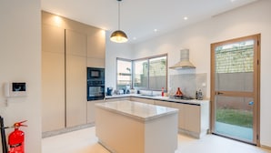 A modern kitchen with a central island, built-in appliances, and a large window providing natural light. - Villa Yas - 5-Stars - Heated Pool - Driver - Chef - Games - 15min to City Center (Marrakech)