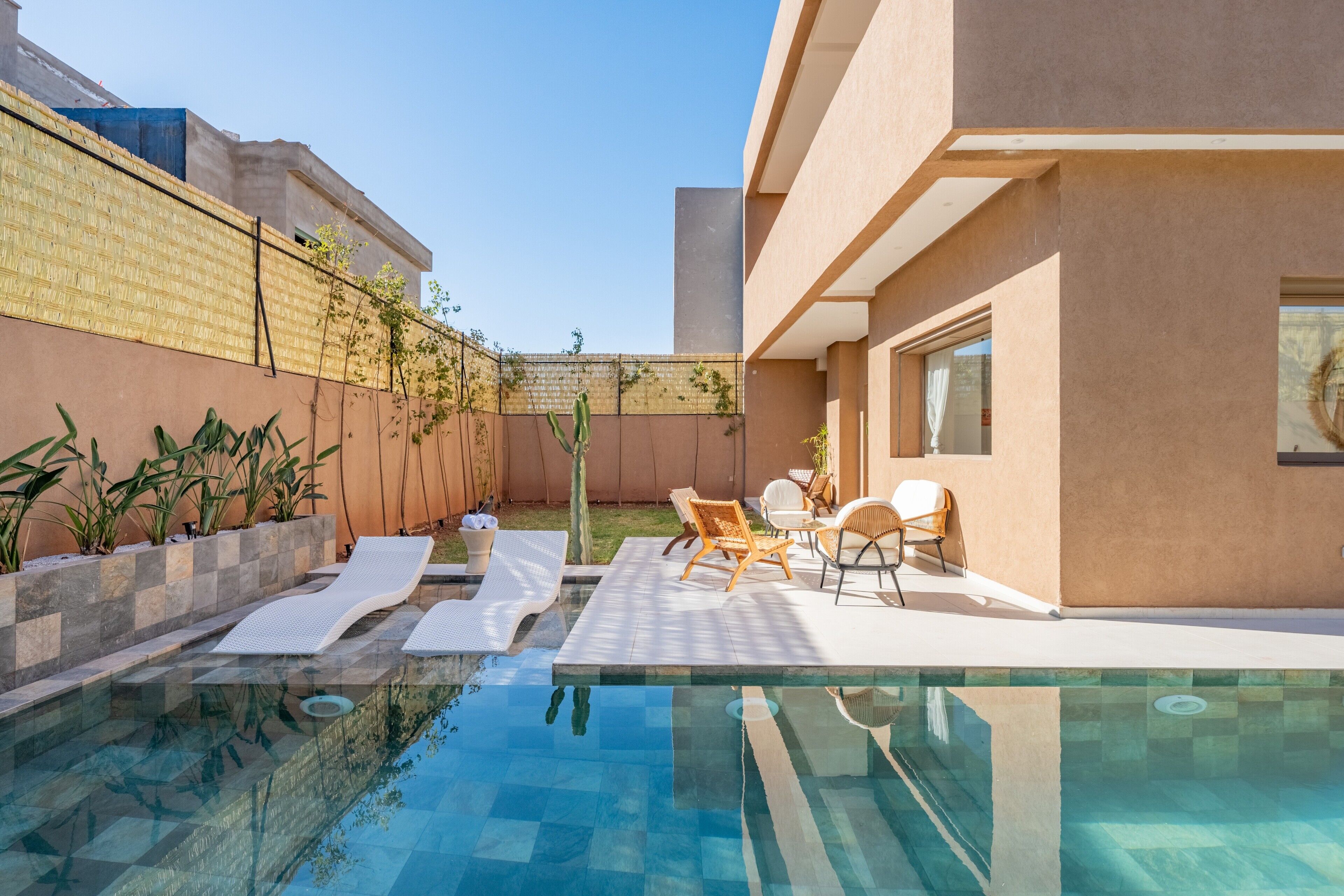 Un área de piscina moderna al aire libre con sillones de descanso y una terraza.