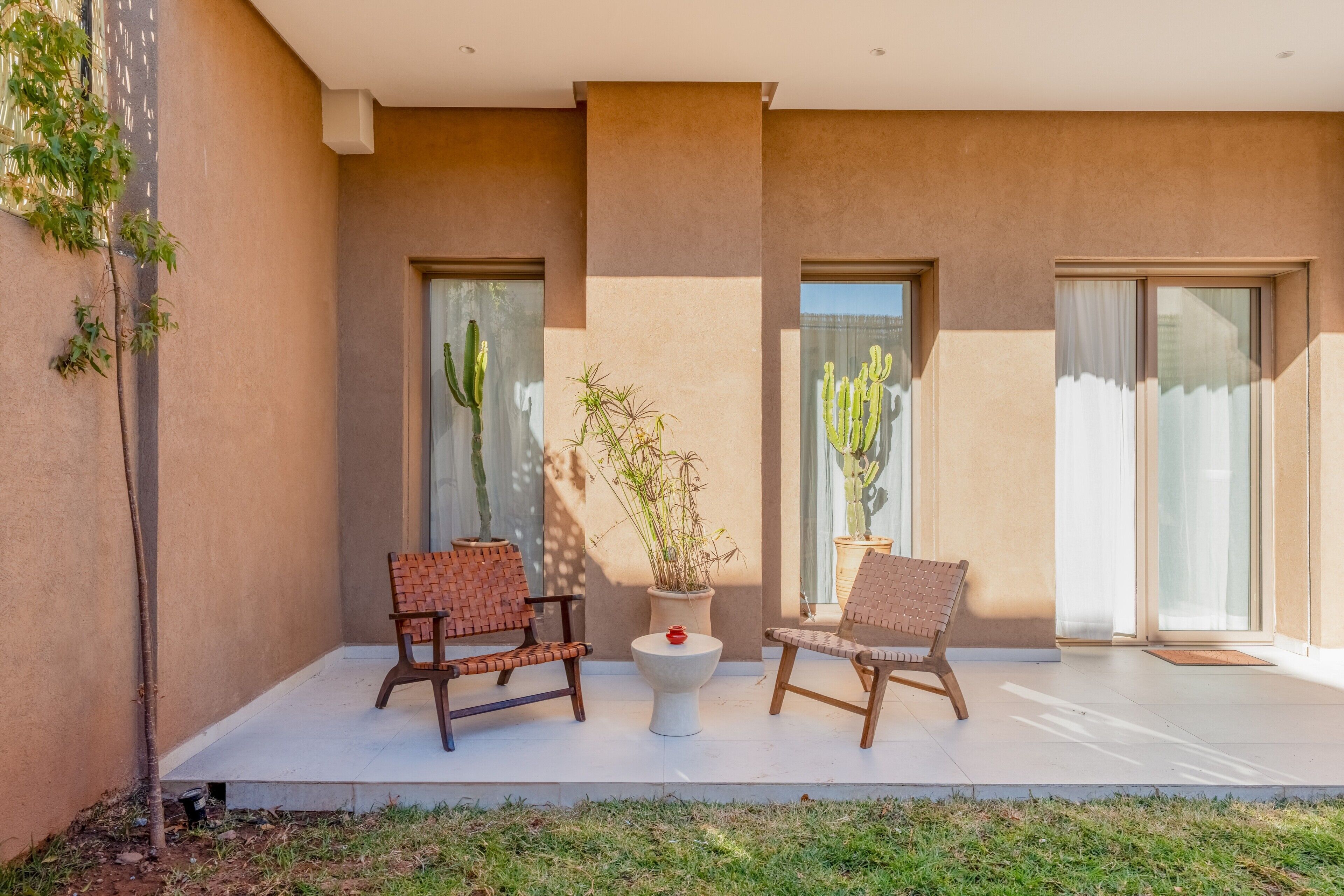 Un espace patio aménagé avec deux fauteuils en osier, une petite table et une plante en pot.