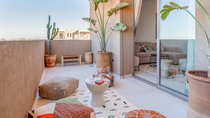 A balcony with potted plants, a seating area, and a view of the cityscape. - Villa Yas - 5-Stars - Heated Pool - Driver - Chef - Games - 15min to City Center (Marrakech)
