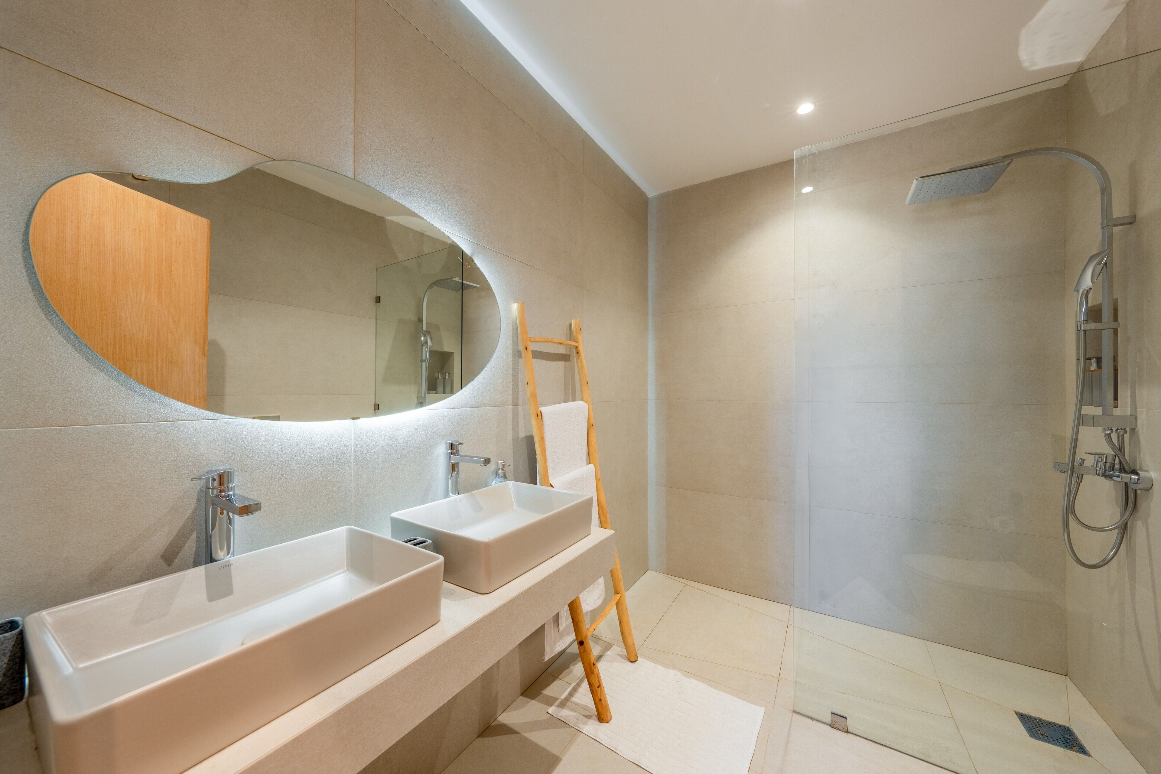 A modern bathroom with two sinks, a large mirror, and a shower.