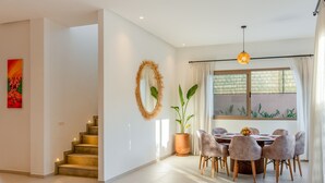 A modern interior with a staircase, a dining area with a round table and chairs, a large mirror, and a potted plant. - Villa Yas - 5-Stars - Heated Pool - Driver - Chef - Games - 15min to City Center (Marrakech)