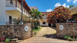 A courtyard with a stone wall, a gate, and a building with a balcony. - Refúgio Tiradentes (Tiradentes)