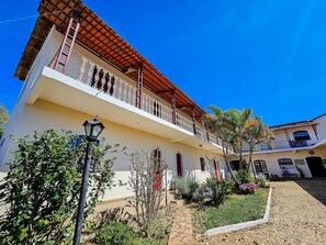 A two-story building with a balcony, a stone pathway, and a well-maintained garden. - Refúgio Tiradentes (Tiradentes)